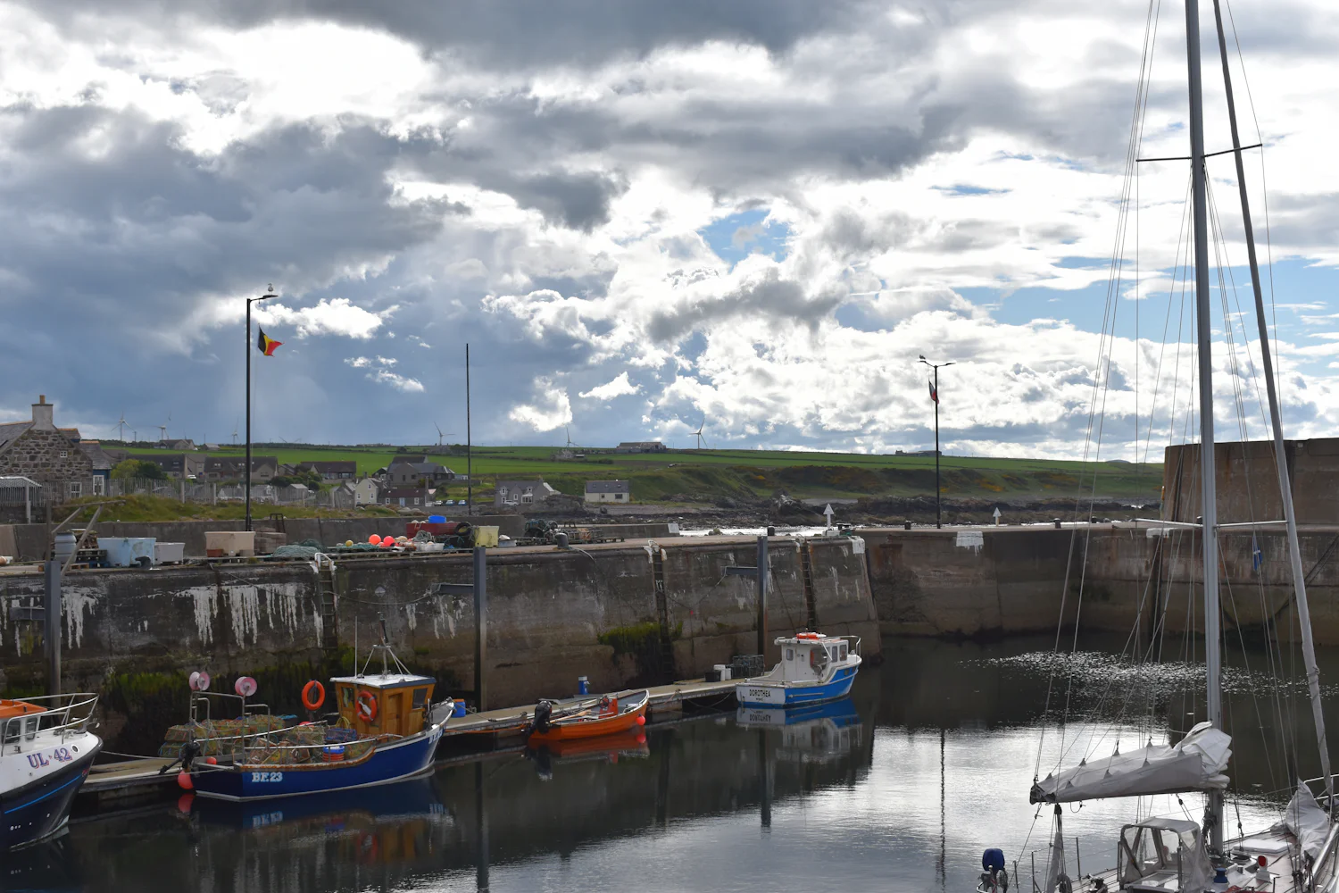 Small boats in a stone harbour under a big cloudy sky