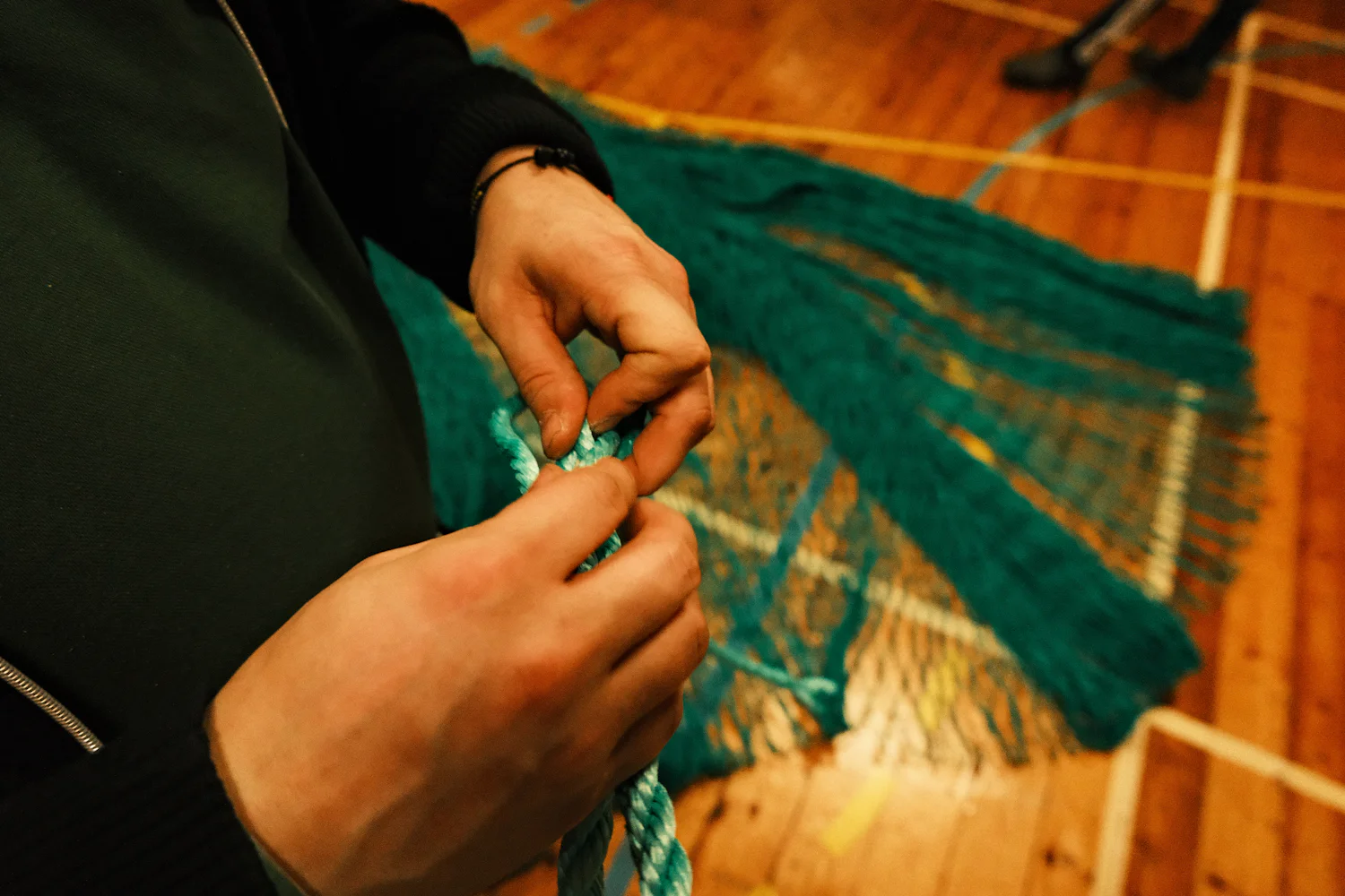 Hands tying a knot in green netting