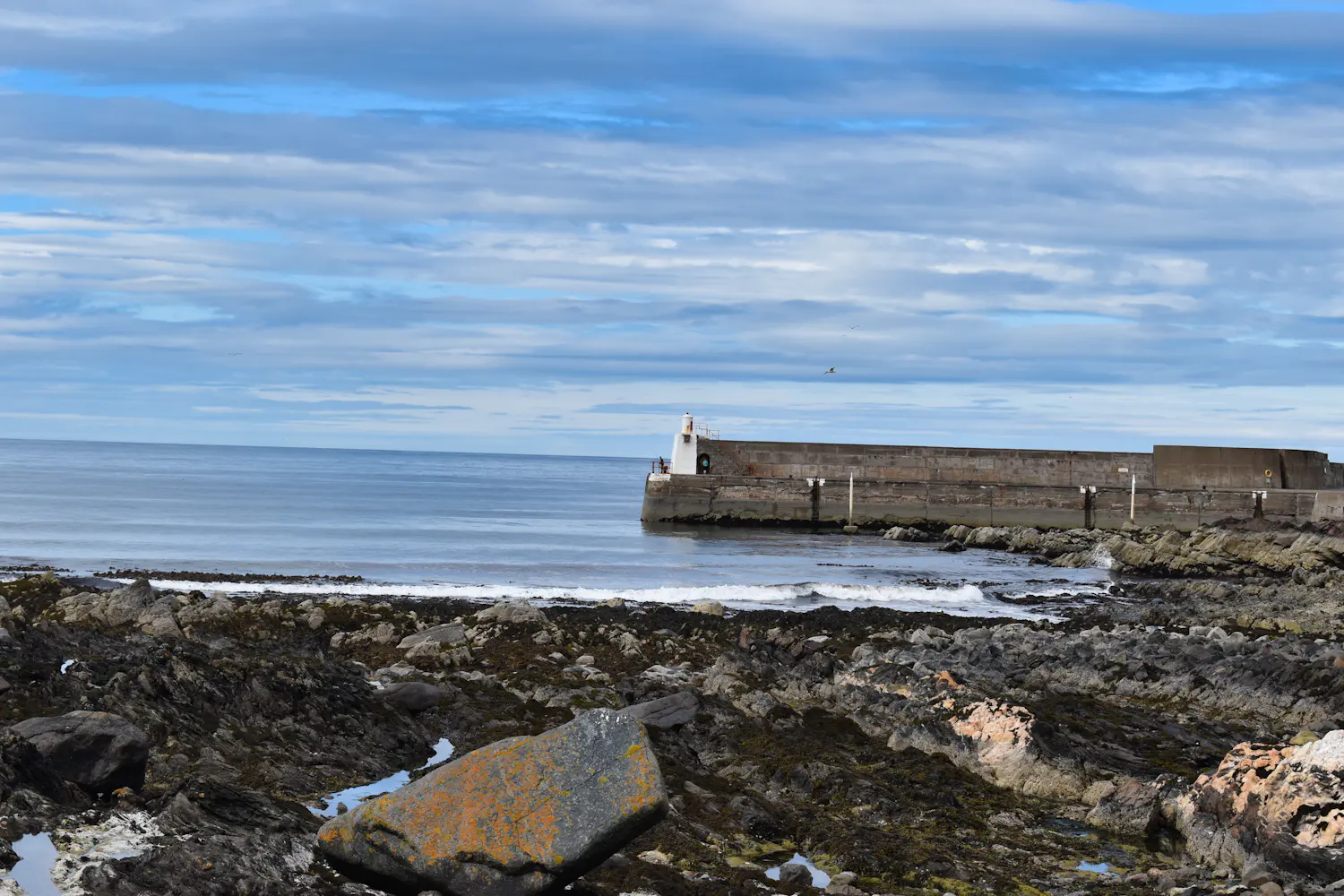 A stone pier on a calm morning over a rocky shore